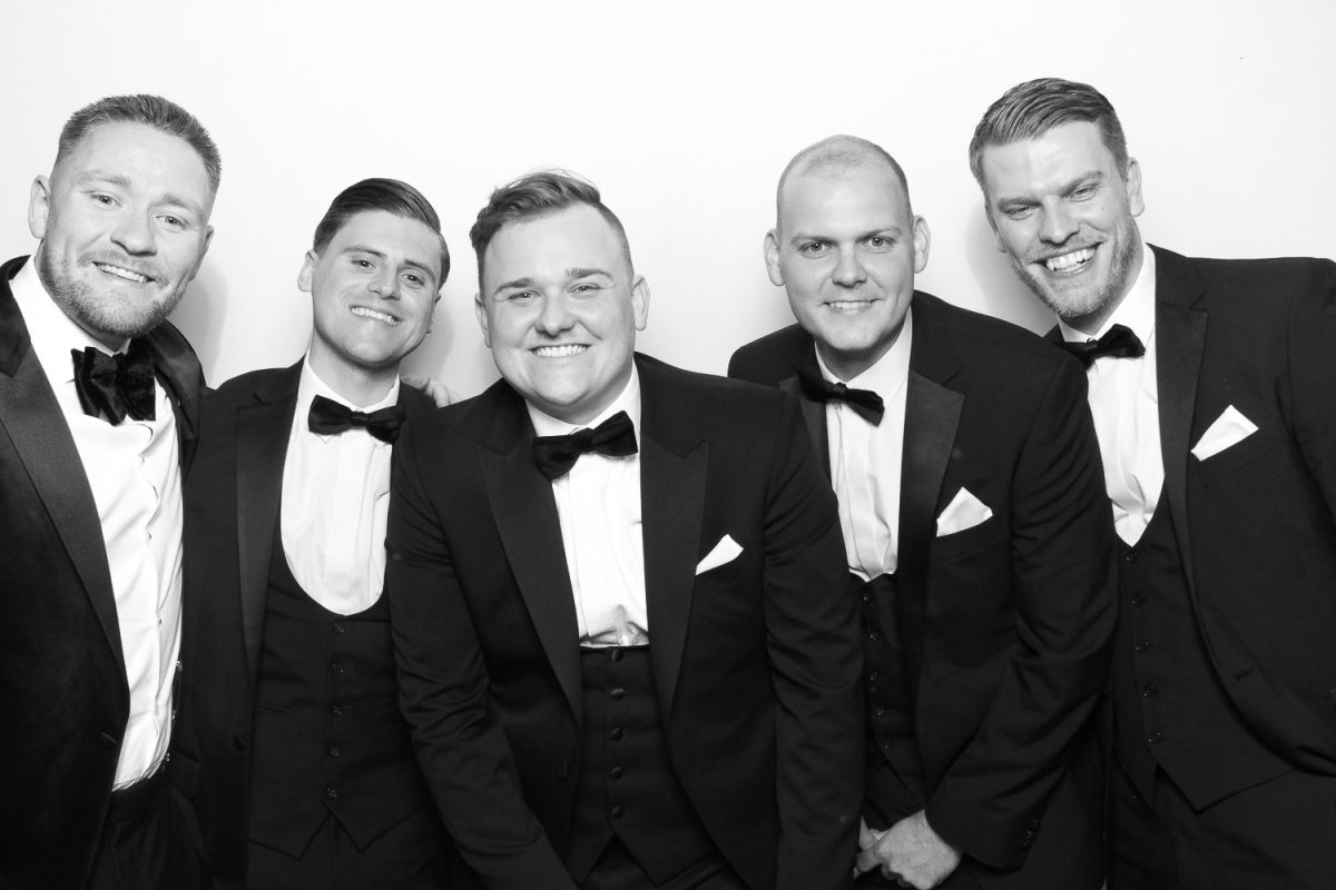 Groom and Groomsmen in tuxedos posing in Photo Booth at Middleton Lodge Wedding