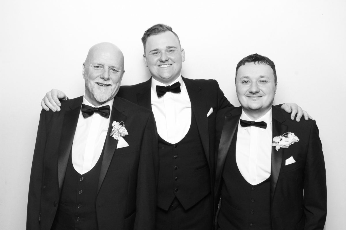 Groom in Black and White Photo Booth with two male guests in tuxedos at Middleton Lodge Wedding